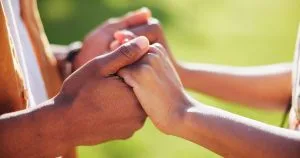 Two hands intertwine gently, symbolizing connection and intimacy
