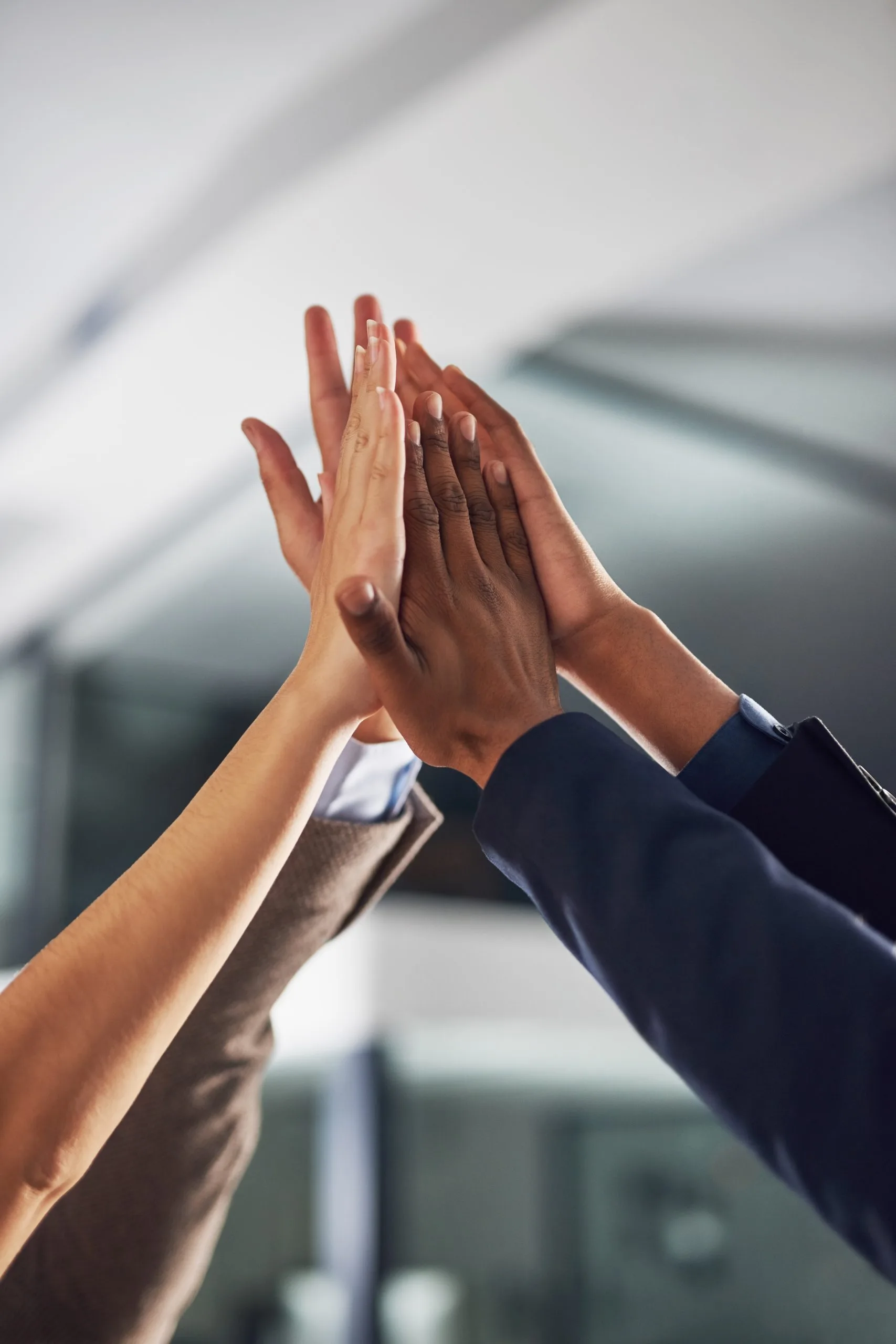 Multiple hands are raised together in a gesture of celebration or agreement